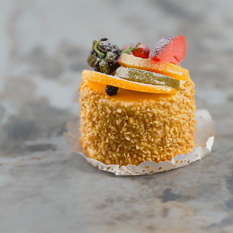 Petit gateau rolled in toasted almonds and topped with candied fruit